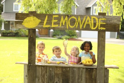 Vintage children's pop up shop lemonade stand with happy children standing behind
