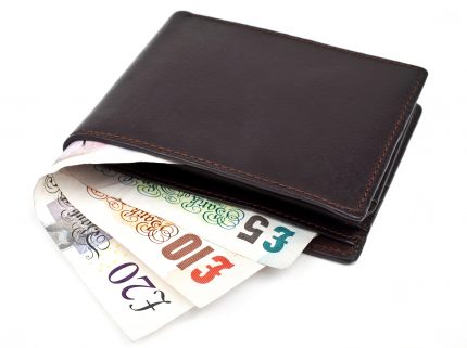 Brown wallet containing money over white background
