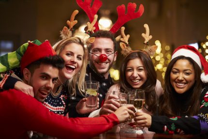 Group of work colleagues smiling with drinks at Company Christmas Party