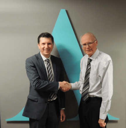 Two Aston Shaw professionals shake hands in front of company logo