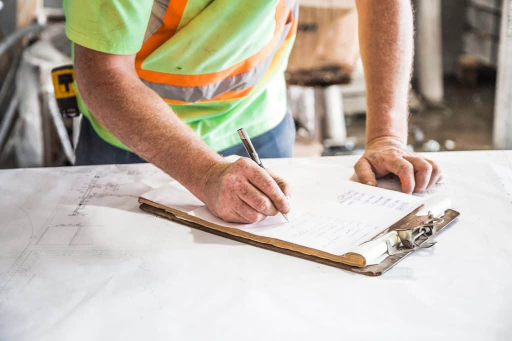 Construction Person Writing on Paper on Top of Table